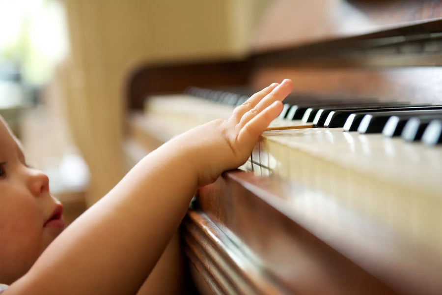Baby's hand reaching up to touch the keys of a piano during music time